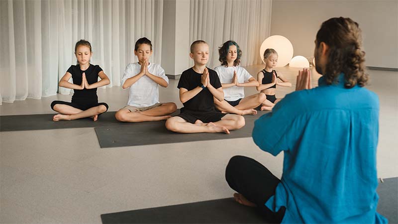 Children Doing Yoga With A Camp Counselor
