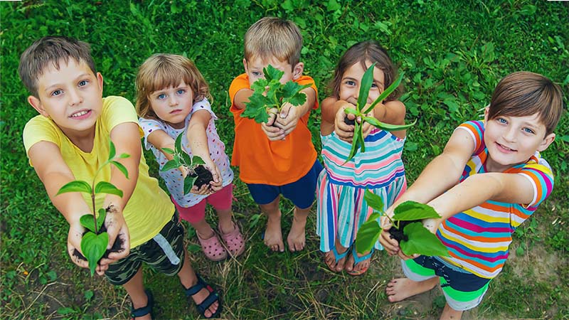Kids holding plants to illustrate environmental friendliness.