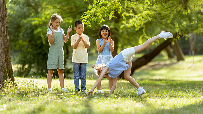 Child doing a cartwheel while three others cheer.