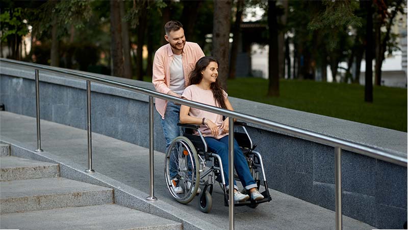 Man Pushing Woman In Wheelchair On A Ramp
